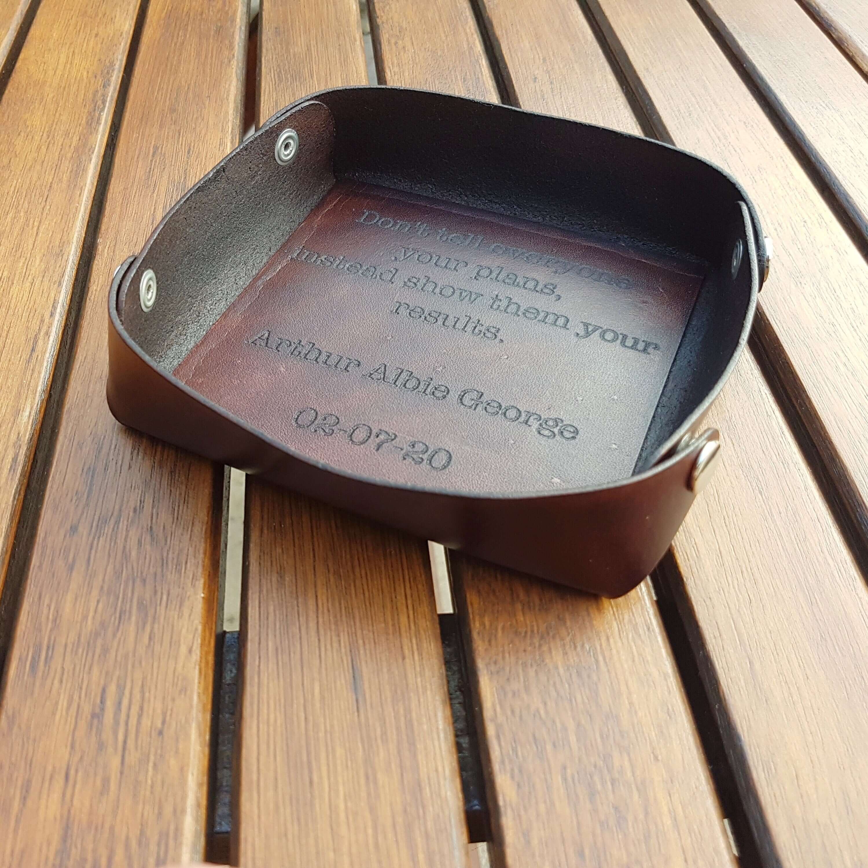 Personalized leather valet tray with laser engraved message, perfect for keys and wallet organization.