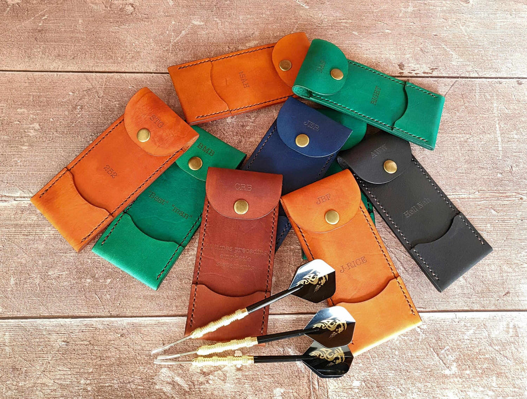Personalized leather darts case collection displayed with darts, showcasing craftsmanship and vibrant colors.