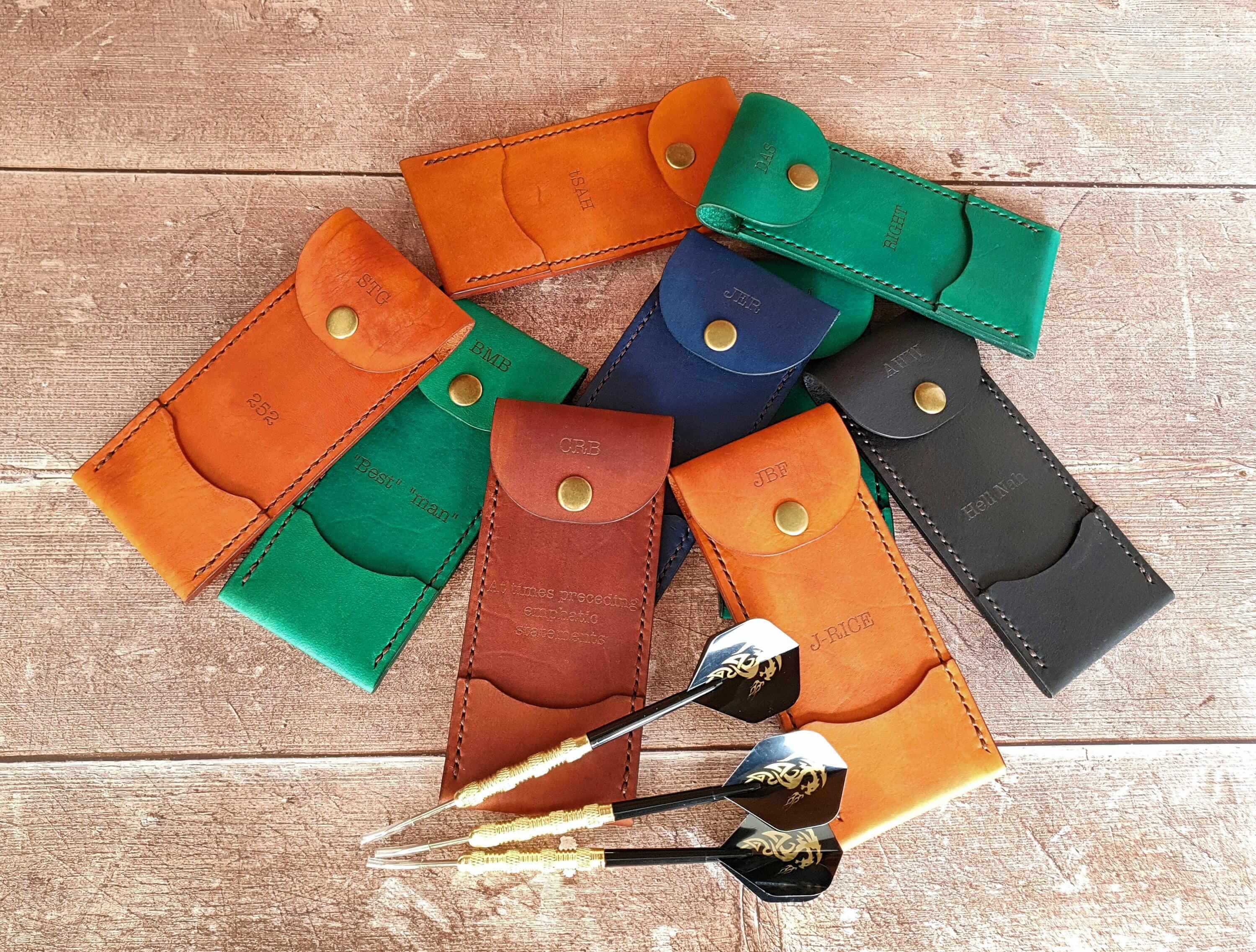 Personalized leather darts case collection displayed with darts, showcasing craftsmanship and vibrant colors.